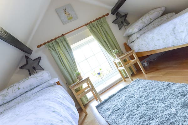 Alternative angle of the cozy attic twin bedroom showing a single bed and sloped ceilings with exposed beams.